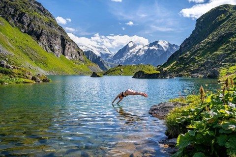 Woman taking a dip, cooling off in the mountain lake Lac de Louvie, behind the summit of the Grand
