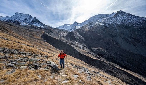 Mountaineers on a hiking trail in Niedertal, snow-covered mountain peaks of the Ötztal Alps with