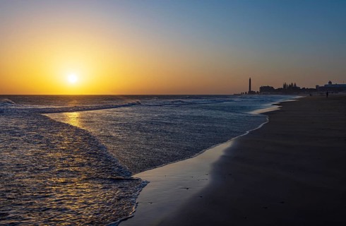 Sunset at the beach of Maspalomas with lighthouse Faro de Maspalomas, Gran Canaria, Canary Islands,