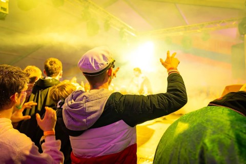 Audience enjoys a brightly lit show at an event, the atmosphere is lively and festive, carnival,