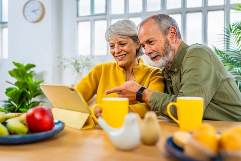 Senior man pointing the screen of a digital tablet with his wife aside