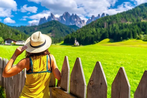 Female tourist wearing a straw hat admiring the stunning view of the odle mountains and st.