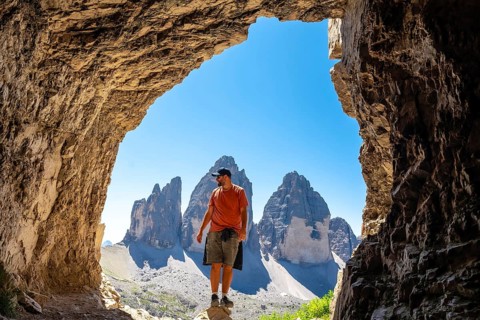 Hiker enjoying the scenic view of tre cime di lavaredo, a symbol of the dolomites, from inside a