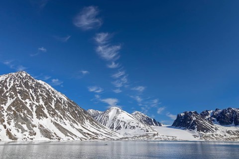 Cirrus uncinus clouds above mountain with glacier along Magdalenefjorden, fjord in Albert I Land on