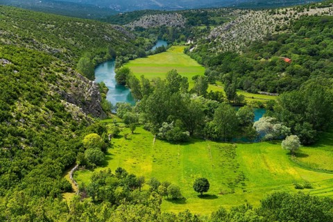 Green valley with river, surrounded by wooded hills and mountains, river Zrmanja near Bilišane