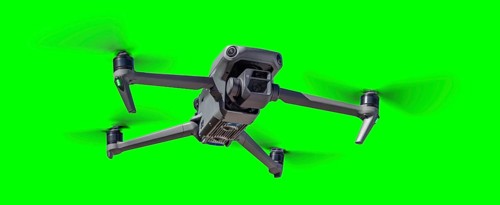 Isolated unmanned aircraft system (UAV) quadcopter drone in the air over A green screen