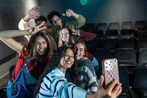 Group of smiling friends taking a selfie at the cinema, enjoying a movie night out together