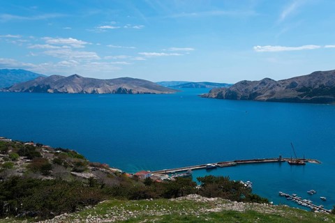 Panoramic view of a harbour on the calm blue sea, surrounded by mountains and islands, view from