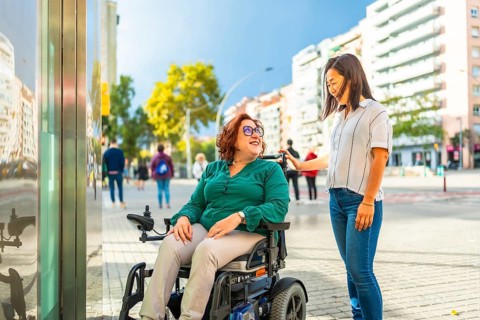 Disabled woman in wheelchair and chinese caregiver waiting at metro elevator in the city during