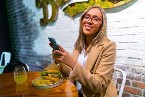 Latin blonde woman using phone while eating in a fast food restaurant