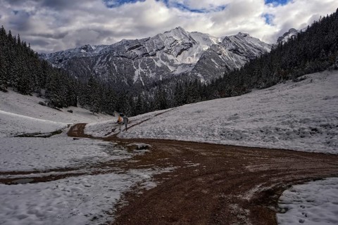Picturesque view of snow-covered mountains on a path in front of dramatic clouds, Krün, Bavaria,