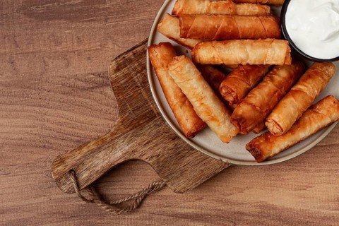 Fried spring rolls with cheese, on a wooden background, with cream sauce, no people