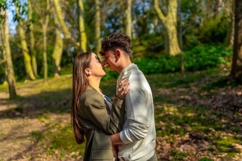 Young couple embracing and sharing a tender moment in a beautiful forest, surrounded by trees and