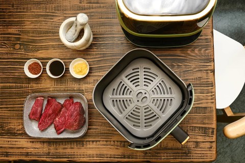 Fresh cuts of meat are arranged alongside several bowls of spices and sauces on a wooden table. A