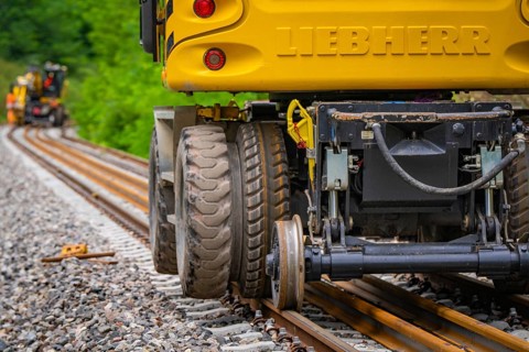 Close-up of the tyres of a yellow construction machine on rails, track construction, Hermann