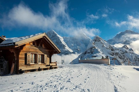 Wooden chalet and ski slope, with views of the Eiger, Mönch and Tschuggen, Grindelwald, Bernese