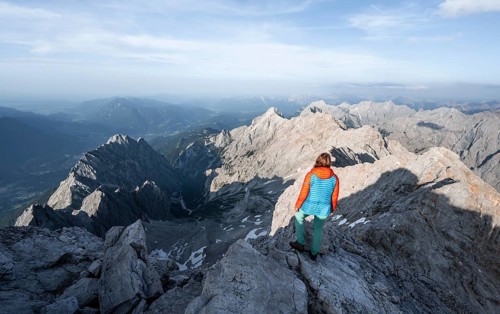 Mountaineer on a narrow rocky steep mountain ridge, view into the Höllental and to the Alpspitze
