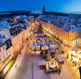The snow-covered Christmas market with St Wolfgang's church seen from the town hall tower,