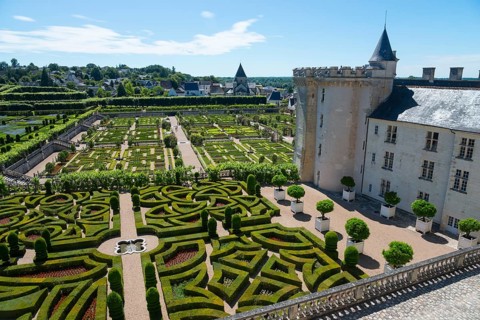 Castle with adjoining, geometrically designed garden with hedges and well-tended paths on a sunny