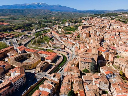 Aerial view of a historic town with tiled roofs and a hilly landscape in the background, aerial