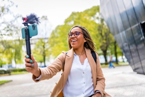 Happy latin woman influencer vlogging while walking along the city