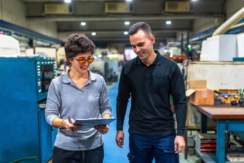 Woman manager and male worker walking checking stock inventory with clipboard and discuss talking