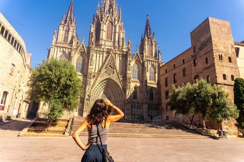 Young woman shielding her eyes from the sun while contemplating the majestic barcelona cathedral in