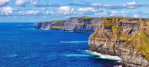 Sweeping views of steep cliffs and azure sea under a cloudy sky, Cliffs of Moher