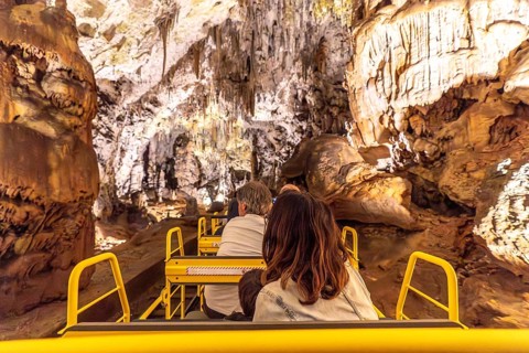 Tourists enjoying a train ride inside the magnificent postojna cave, a famous natural wonder in