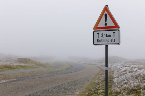 Road in the fog with traffic sign, attention, dune landscape on Norderney, Lower Saxony, Germany,