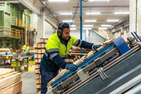 Male caucasian worker of a recycling plant repairing a pallet for reuse in the workshop