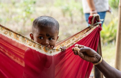 Children of tea plantation workers takes care by daycare worker underneath a tent as their mothers