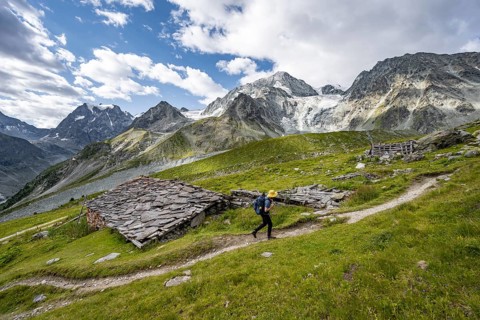Mountaineers on a hiking trail, Alpine huts covered with slate slabs, mountain landscape near