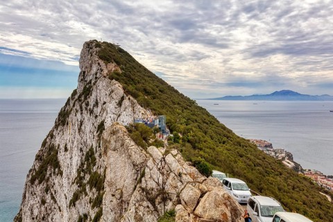 Steep rocky outcrop with cars along the coast and views of the sea, Gibraltar, Europe