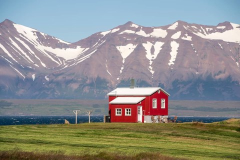 Red house near Dalvik or Dalvik, mountains with snow remains, Eyjafjörður or Eyjarfjörður or