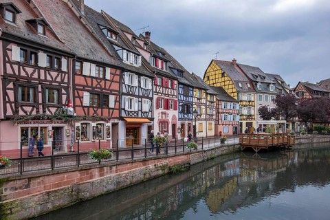 Colourful half-timbered houses on a quiet canal in a historic old town with a cloudy sky, Petite
