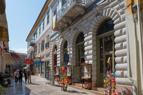 Lively shopping street with historic buildings, shop windows and colourful windmills under a blue