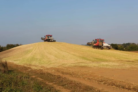Piston Bully tracked bulldozer vehicles building silage clamp of sweetcorn maize in field stored