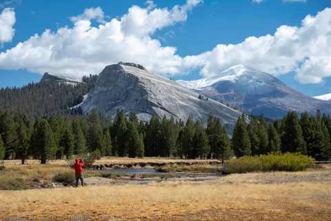 Yosemite National Park, California - A man takes pictures of Lembert Dome above Tuolumne Meadows in