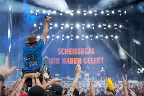 A wheelchair user with pyro in his hand is carried over the audience during the performance of the