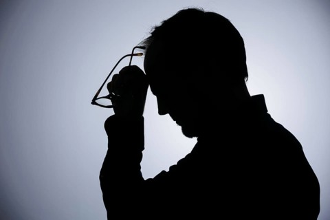 Symbolic photo on the subject of overload. Silhouette of a man rubbing his aching head. Berlin,