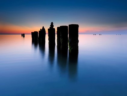 Stone pyramids on old groynes with algae in the water on the beach of the Baltic Sea, long exposure