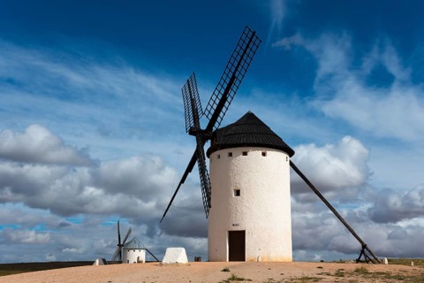 White windmill under a dramatic sky with other mills in the background, Campo de Criptana, Ciudad