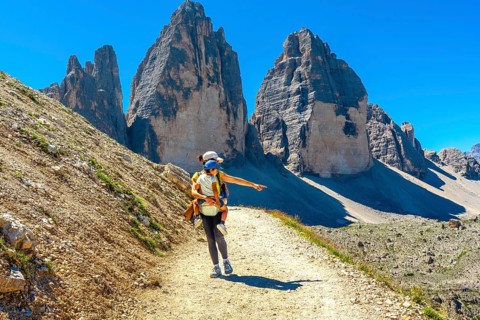 Woman carrying child hiking and pointing at the landscape near tre cime di lavaredo, dolomites, a