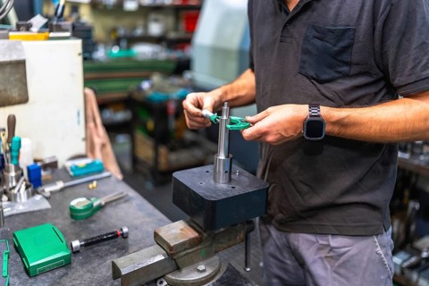 Close-up of unrecongizable man measuring metal pieces using a micrometer in a cnc factory