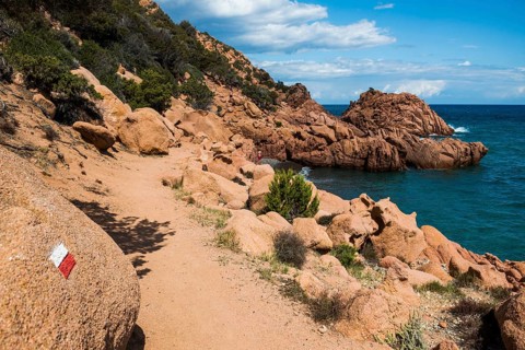 Hiking trail along the coast with red rocks and sea, Spiaggia di Coccorocci, near Tertenia,