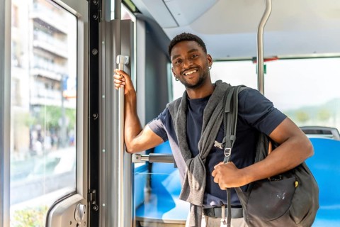 Confident handsome african student on the bus on the way to university