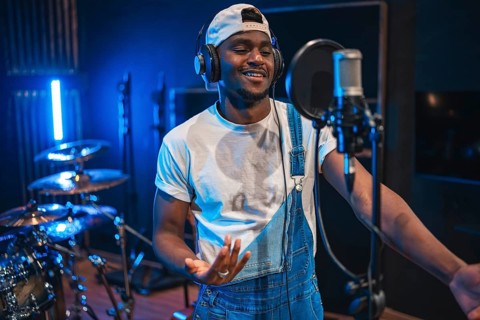 Young, happy african american male artist singing passionately in a professional music recording