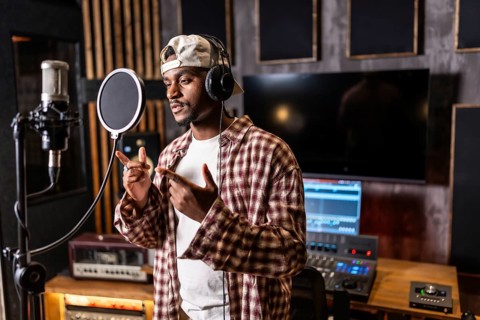 Young man recording vibrant vocals for an exciting new pop music album in a state of the art