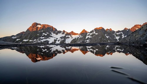 Rocky mountain peaks reflected in a small pond, mountain landscape with alpenglow at sunrise, at